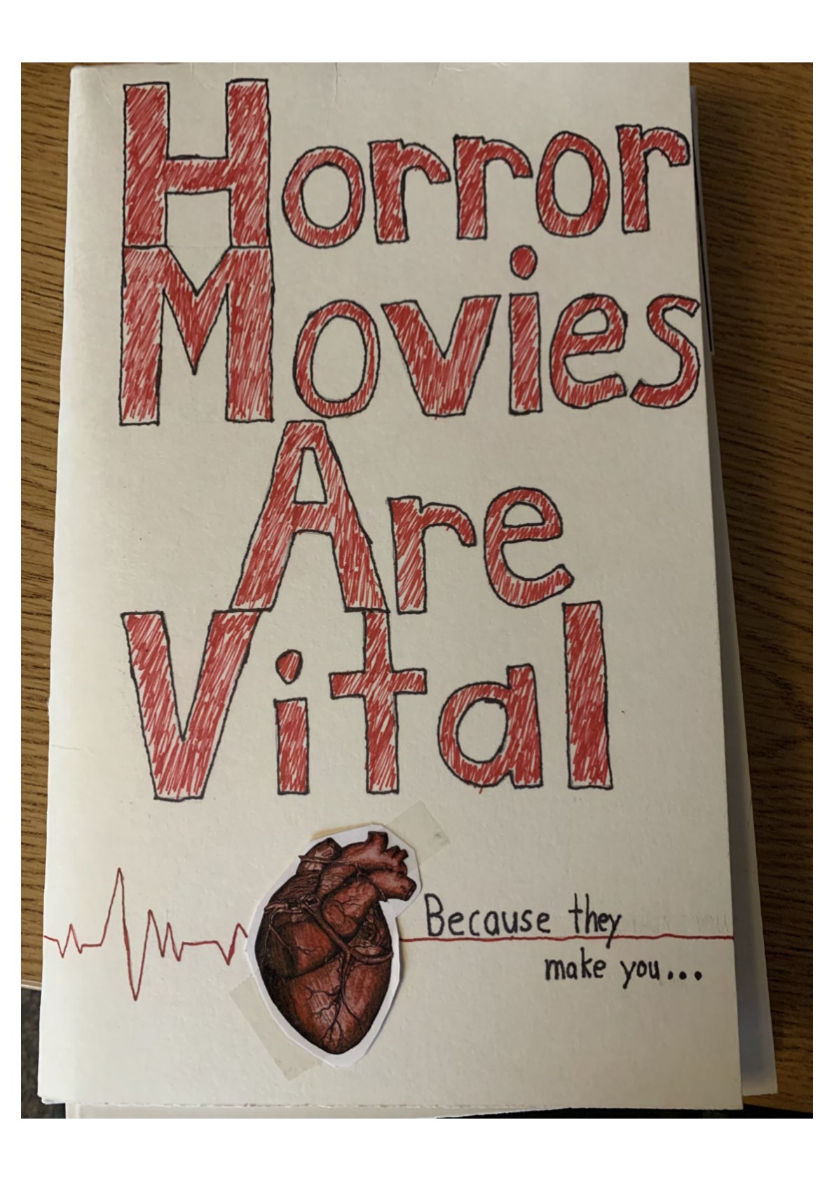 “Horror Movies Are Vital” in large red letters. At the bottom of the page is an EKG line with a realistic heart. Black text reads: “Because they make you…”